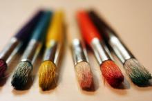 Row of paintbrushes with different colored handles
