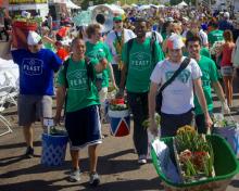 Six young men carry food through a street fair.