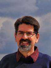Headshot of with dark beard, mustache and glasses