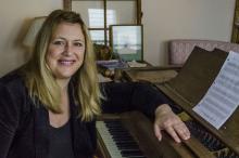 a blonde white woman casually sits at a piano