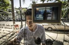 A man interacts with a digital artwork installed in a storefront by writing on glass