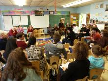 A group of people of diverse ages sit around a classroom discussing a book.