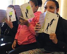 three young woman seated holding open copies of Don't Call Us Dead by Danez Smith