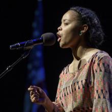 a young black woman  is speaking emotively into a microphone