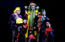 Four people in colorful costumes and facepaint on a stage. 