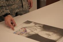 A hand pointing to a drawing of a man. 