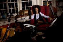 Woman sitting in room surrounded by bass instruments. 