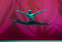 Man in mid-air with arms and legs extended during dance move. 