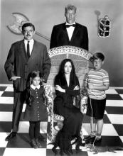 A black-and-white image of three adults (one woman and two men) and two children (one boy and one girl) .