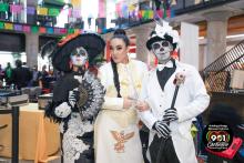 Three people two of whom have painted their faces for Dia de los Muertos
