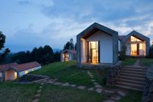 Small housing units lit from within sit atop a grassy hill with stone steps leading up to them