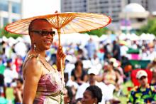 Woman standing outdoors at a festival holding a decorative umbrella.