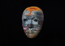 An intricately painted mask in mostly shades of grey with words of inspiration and hope 