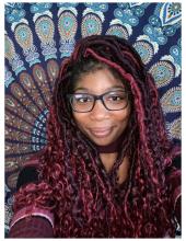 Photo of Zephaniah Galloway in front of a colorful tapestry