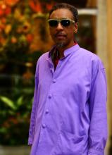 Portrait of man in purple shirt wearing sunglasses.