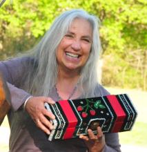 A woman hods a box with colorful designs.