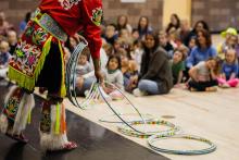 Native man performing a Hoop dance at an elementary school. 