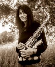 A woman in a field holding a saxophone.