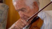 Close-up of a man with white hair playing the violin