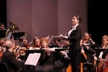 Woman in tux leading an orchestra. 