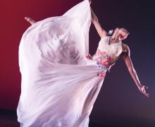 Dancer in white dress in an extended ballet position