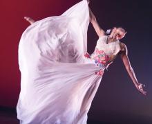 Dancer in white dress in an extended ballet position