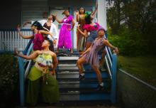 Black women dancers standing on the stairs of a porch.