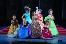6 actresses in various costumes onstage during a scene from Cinderella