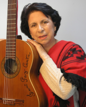 A woman poses with a guitar.