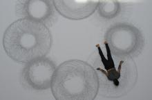 Man lying on paper with charcoal and drawing circles. 