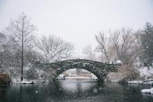 A stone bridge over a pond in the snow