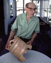 A man holding a carved wooden piece.