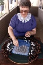 A woman workoing on a  of craft piece.