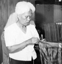 A woman holds a piece of  cloth.