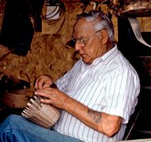 A man weaving a wicker basket.