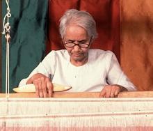 A woman sitted at a loom.