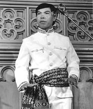 A man in traditional dress gestures with his hands.