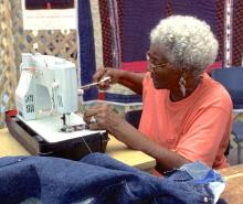 A woman stiing at a sowing machine.