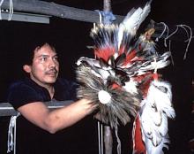 Man holding up a feather headdress.