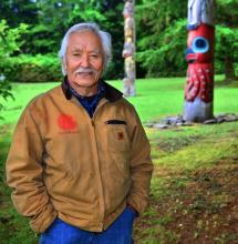 A man poses near a totem.