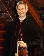 A man poses with a violin.