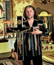 A man holding a carved crusifix.
