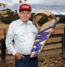 A man holding a traditional baby crib. 