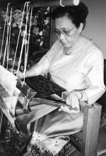 A woman sitting at a weaving loom.