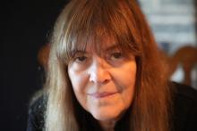Close-up of white woman with long, straight brown hair staring into camera.