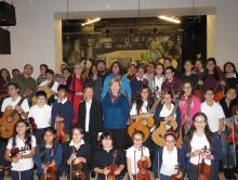 Jane Chu and Senator Tammy Baldwin with a large group of kids holding stringed instruments