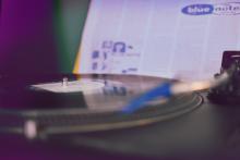 photograph of record player with record and back cover of a Blue Note album in the background