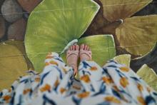 A woman in heels in a flower dress stepping over a sidewalk painting.