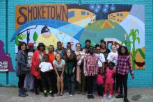 A group of women standing in front of a mural. 