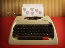 a manual typewriter with a sheet of paper in the roller with hearts on it